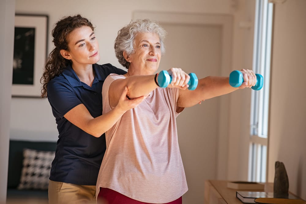 Staff helping resident lift weights at Vista Prairie at Copperleaf in Willmar, Minnesota