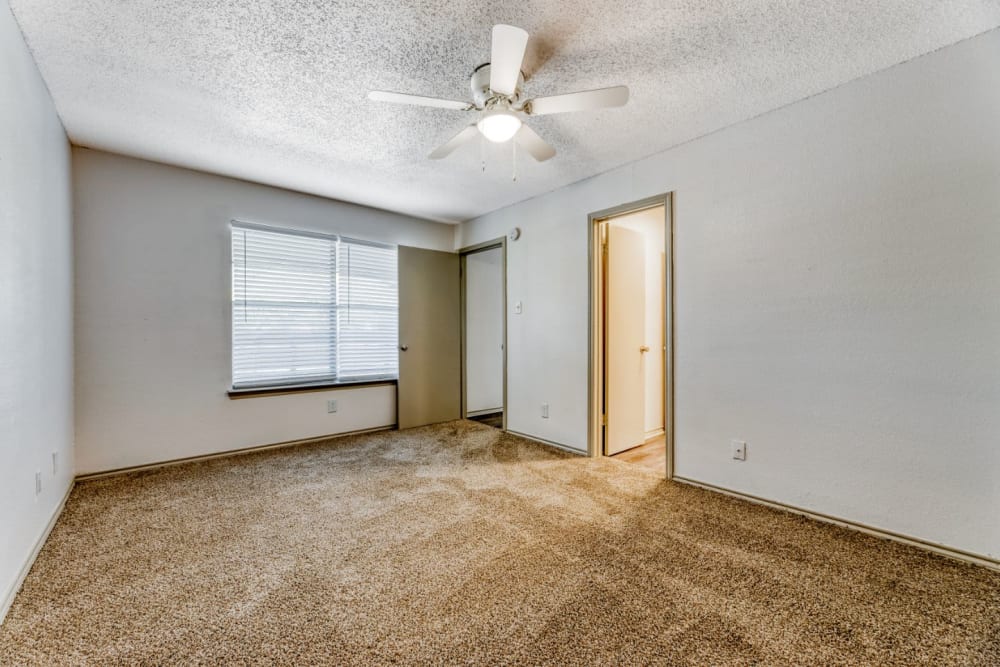 An unfurnished bedroom with ceiling fan, closet and large window at Marshall Apartment Homes in Balch Springs, Texas