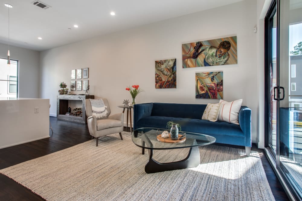 Spacious apartment living room with large area rug and blue sofa at The Collection Townhomes in Dallas, Texas