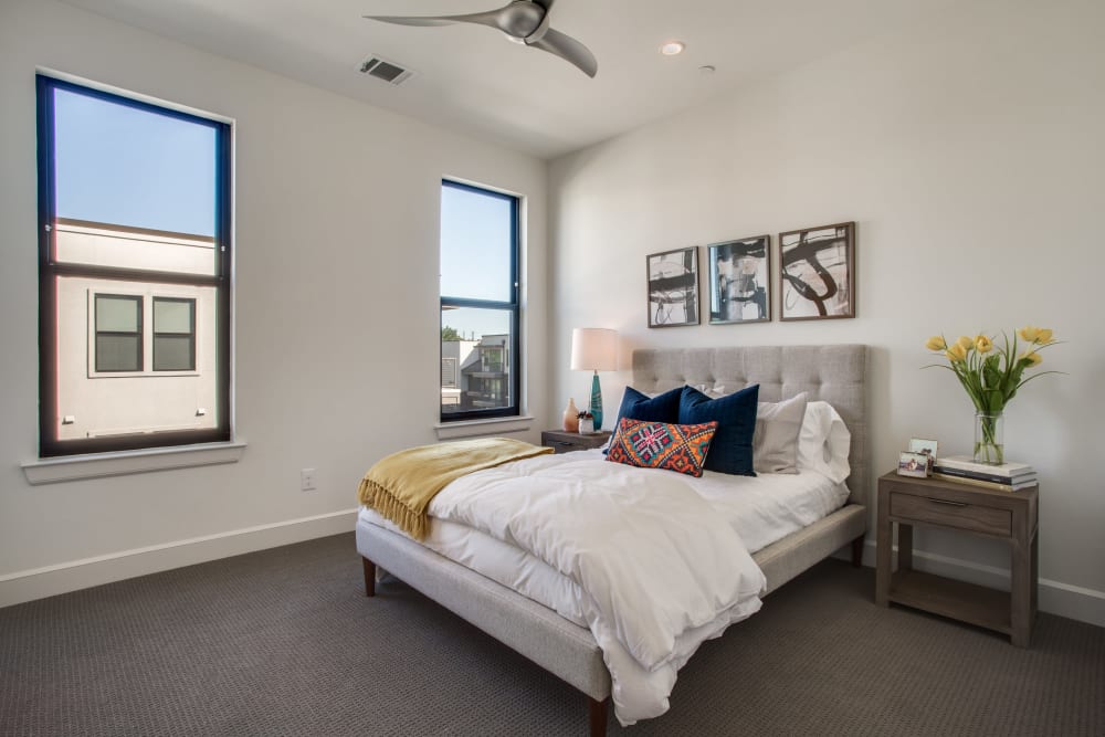 Carpeted apartment bedroom with two windows at The Collection Townhomes in Dallas, Texas