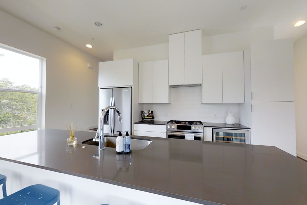 Modern kitchen with white cabinets and granite counters at The Collection Townhomes in Dallas, Texas