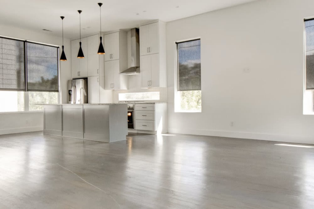 Large open concept living room and kitchen with grey hardwood floors at The Collection Townhomes in Dallas, Texas