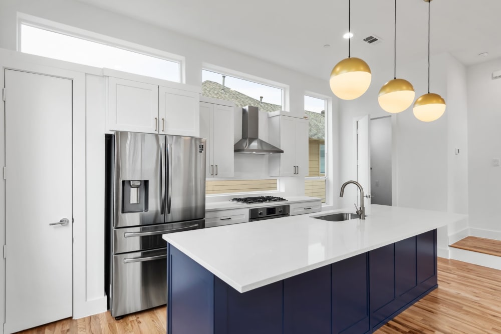 Modern kitchen with large island and stainless steel fridge at The Collection Townhomes in Dallas, Texas