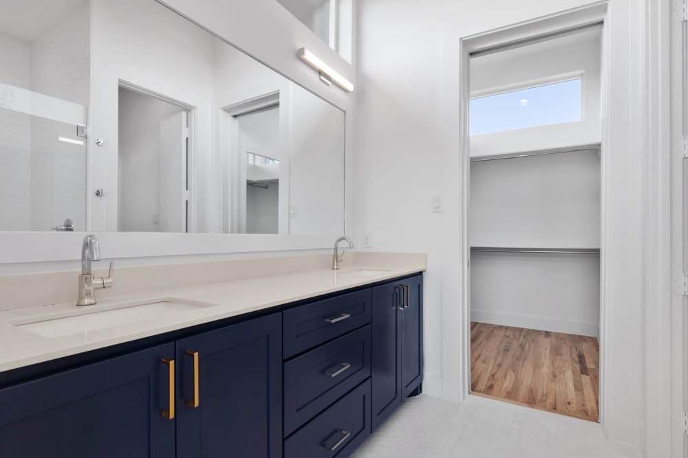 Large bathroom with dark blue cabinets and large mirror at The Collection Townhomes in Dallas, Texas