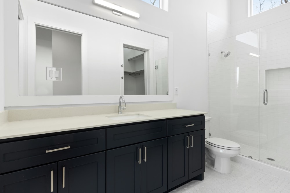 Large bathroom with black cabinets and large mirror at The Collection Townhomes in Dallas, Texas