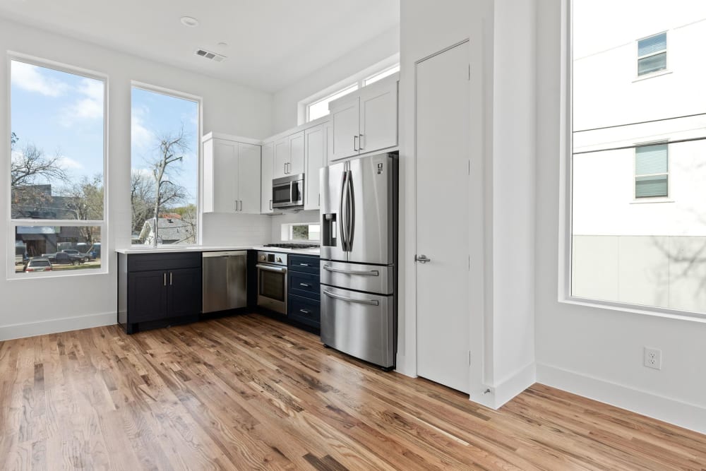 Spacious open concept living area with hardwood floors and stainless steel kitchen appliances at The Collection Townhomes in Dallas, Texas