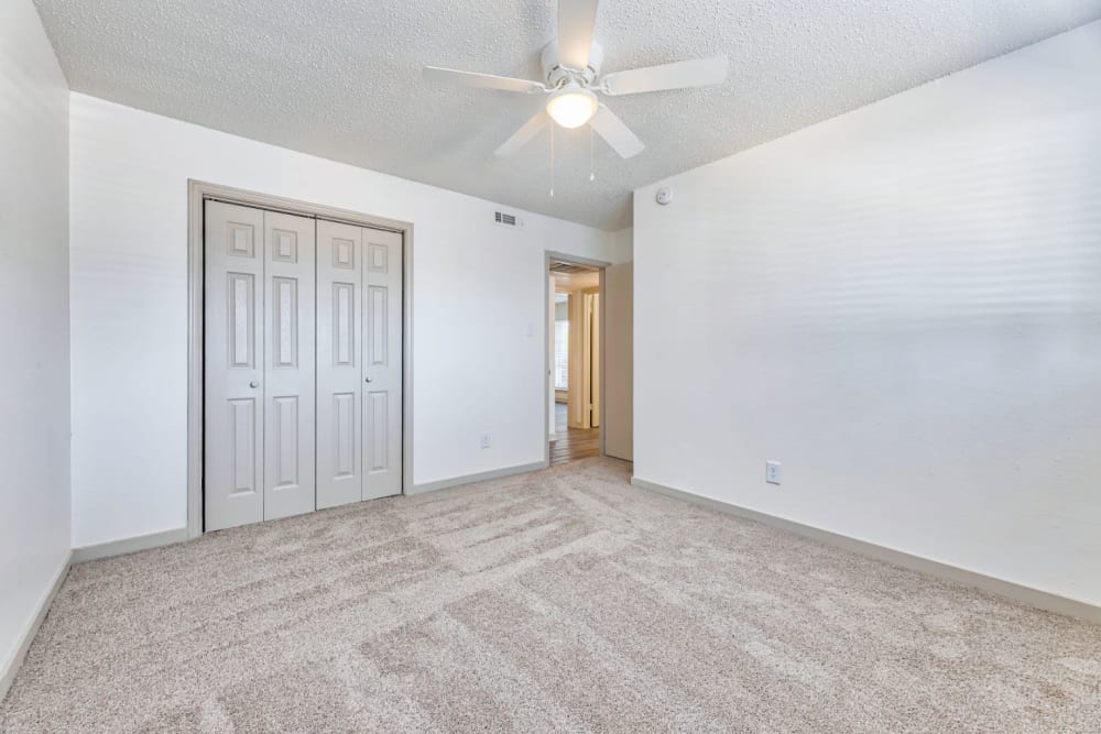 An unfurnished bedroom with large closet and ceiling fan at Lovato Apartment Homes in Garland, Texas