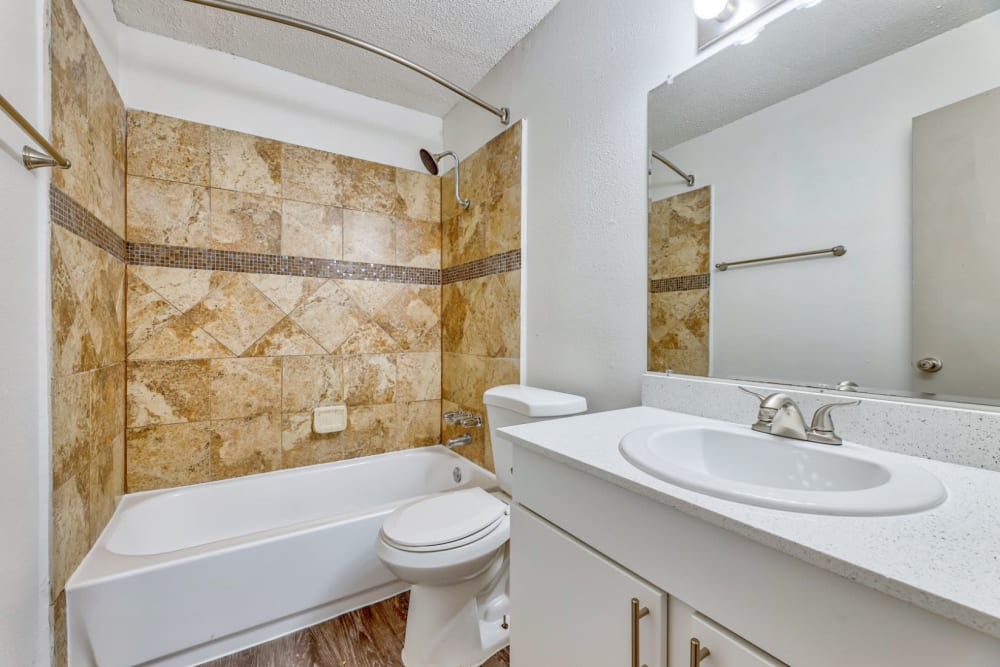Gorgeous bathtub with tiled walls and vanity at Lovato Apartment Homes in Garland, Texas