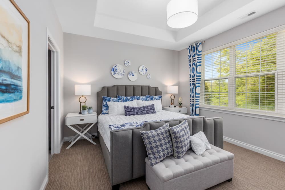 Well-furnished bedroom with floor-to-ceiling windows in a model home at Noble on the Lake in Brighton, Michigan