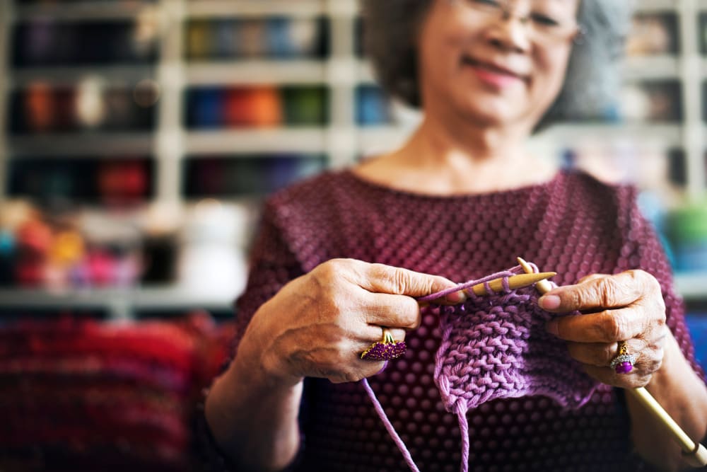 A resident knitting with purple yarn at Brightwater Senior Living of Capital Crossing in Regina, Saskatchewan