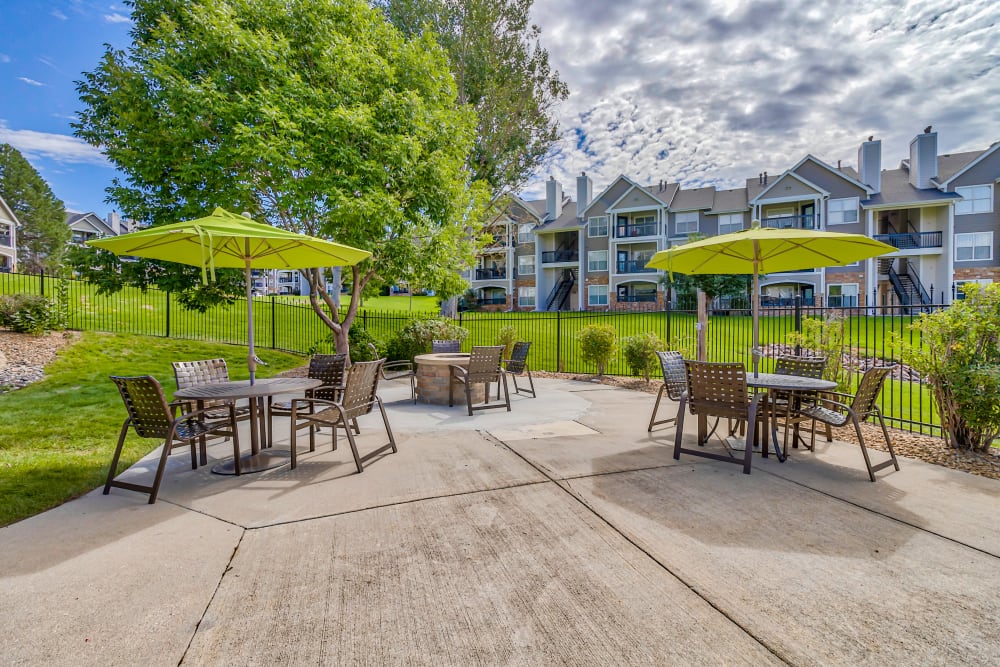 Outdoor community patio tables with sun shade umbrellas at The Pines at Castle Rock Apartments in Castle Rock, Colorado