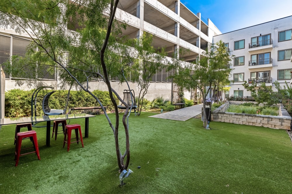 Courtyard with partially shaded hammocks and wood benches along walkway at Marq on Burnet in Austin, Texas
