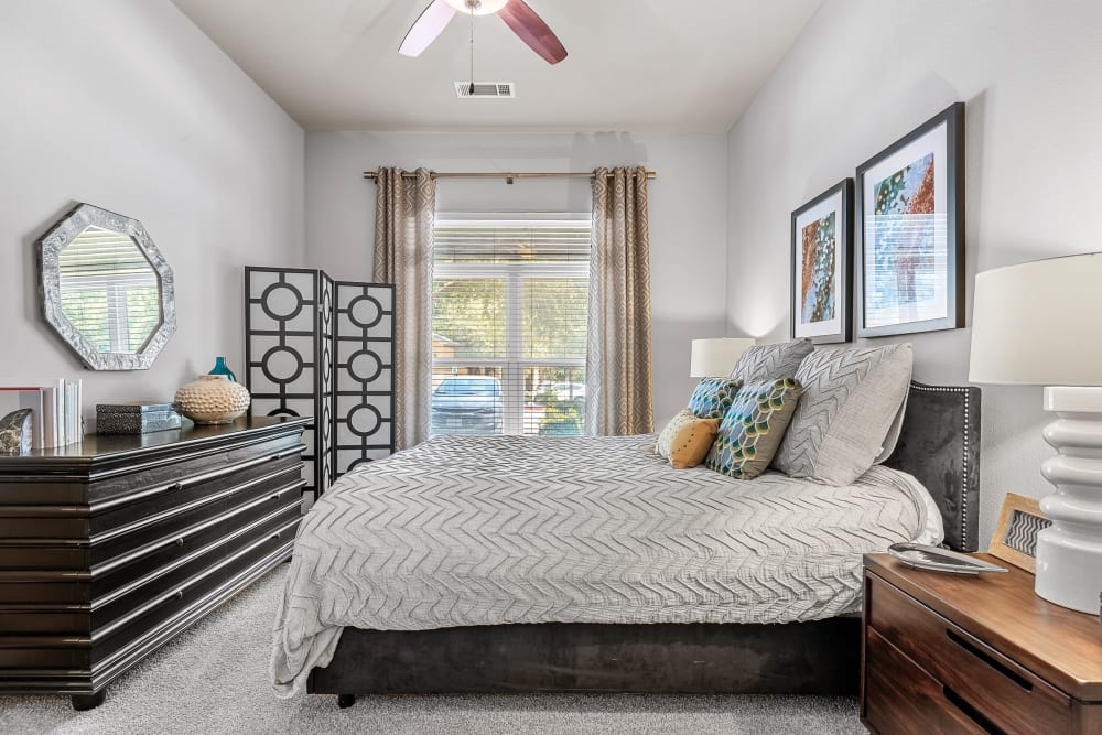 Large bedroom with large window and carpeted floors and celling fan at Marquis at Barton Trails in Austin, Texas