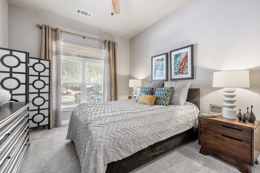 Large bedroom with large window and carpeted floors and celling fan at Marquis at Barton Trails in Austin, Texas