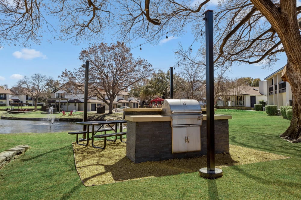 Outdoor grill station with picnic table at Embry Apartments in Carrollton, Texas