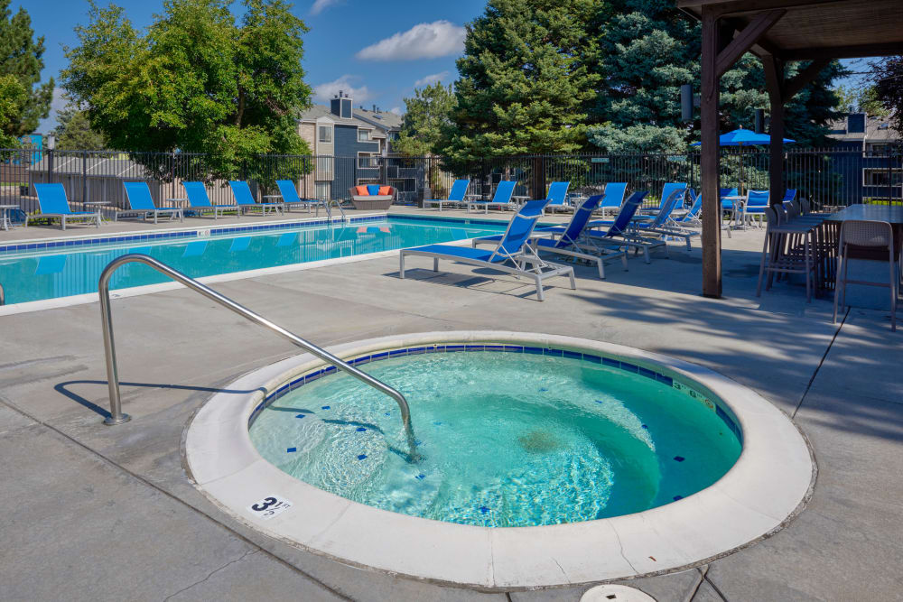Beautiful resort-style swimming pool with lounge chairs and a barbecue area at Alton Green Apartments in Denver, Colorado