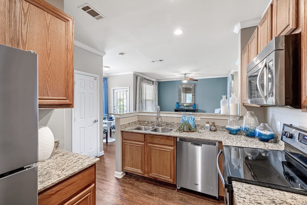 Modern style kitchen with stainless steel appliances, granite countertops, and wood flooring at Marquis at The Cascades in Tyler, Texas