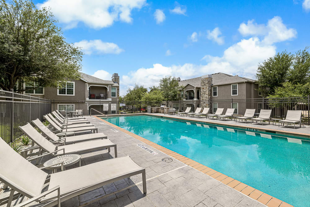Sparkling resort style pool and chairs at Marquis at The Cascades in Tyler, Texas