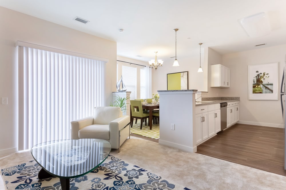 A set dining table, entrance to the kitchen and love seat in the living room of an apartment at Sound at Gateway Commons in East Lyme, Connecticut