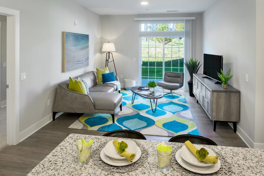 A furnished apartment living room with doors to the patio at Cove at Gateway Commons in East Lyme, Connecticut