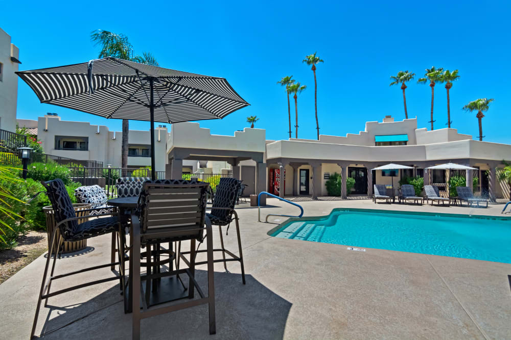 Umbrella shaded seating by pool at Casa Santa Fe Apartments in Scottsdale, Arizona