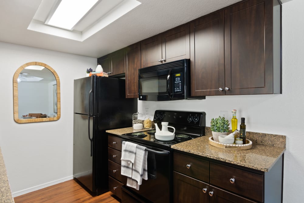 Kitchen featuring dark wood cabinets and black appliances at Casa Santa Fe Apartments in Scottsdale, Arizona