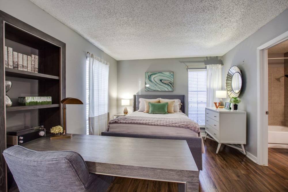 A desk and chair at the end of a bed in a bedroom at Verandahs at Cliffside Apartments in Arlington, Texas