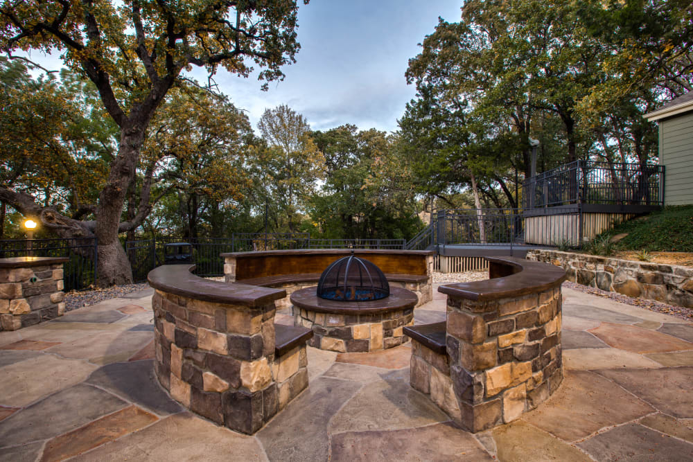 A firepit surrounded by brick made seating at Verandahs at Cliffside Apartments in Arlington, Texas