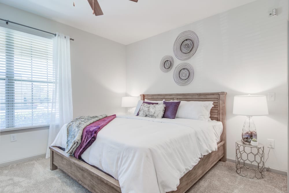 A king sized bed in an apartment bedroom with an attached bathroom at Bradley Park Apartments in Cumming, Georgia