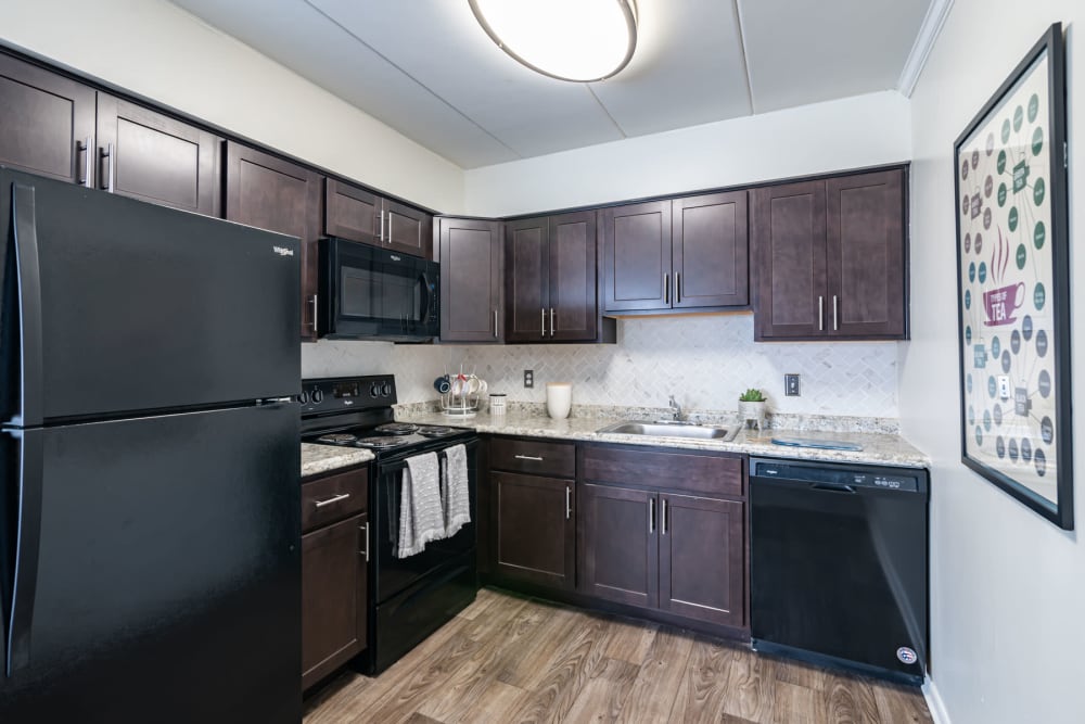 Kitchen with espresso cabinets and black appliances at William Penn Village Apartment Homes in New Castle, Delaware