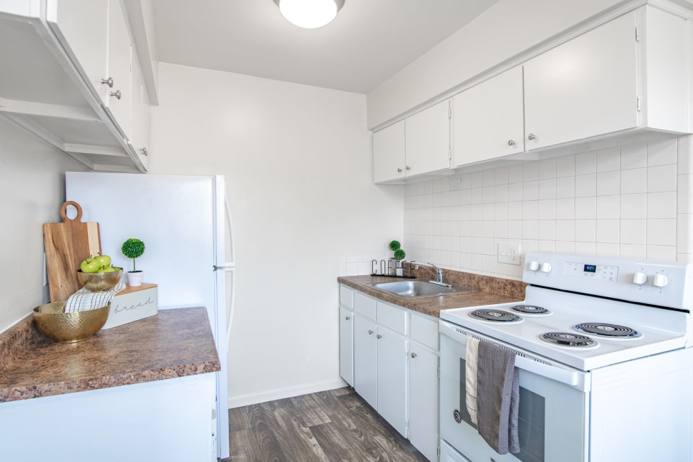 Kitchen with original white cabinets, vinyl plank flooring, and white appliances