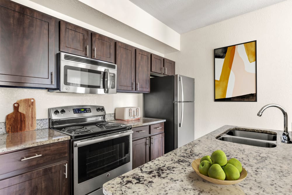 Model kitchen with dark wood cabinets at Harbortown Apartments in Orlando, Florida
