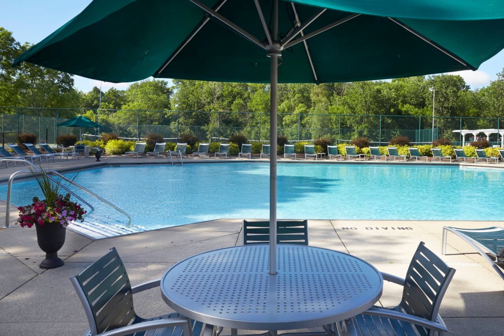 Patio table with an umbrella by the inviting outdoor pool at Muirwood in Farmington Hills, Michigan