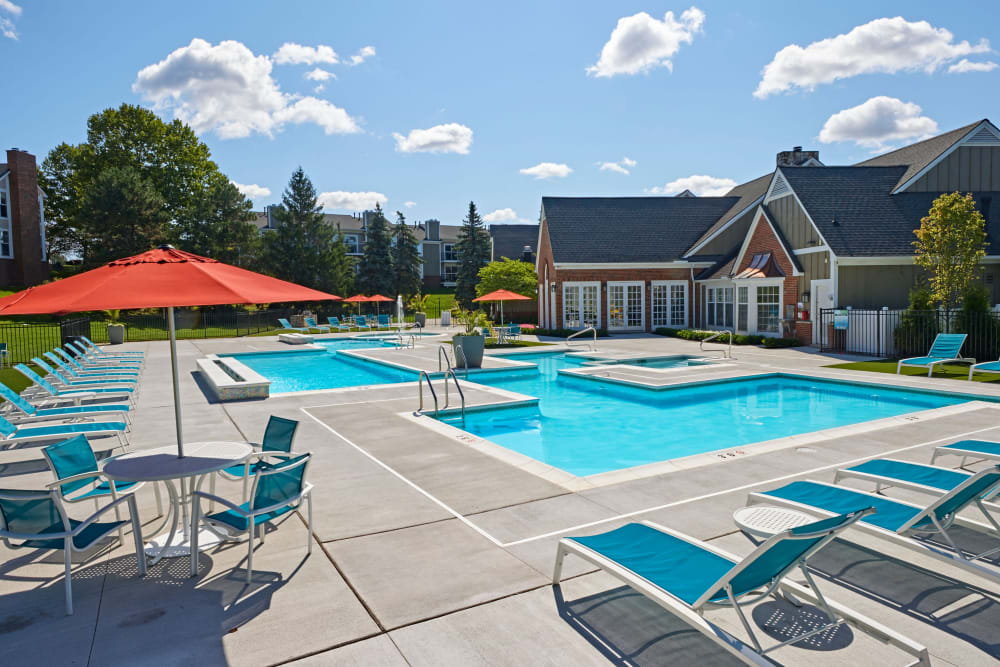Outdoor swimming pool with a hot tub and pool deck lounge furniture at Citation Club in Farmington Hills, Michigan