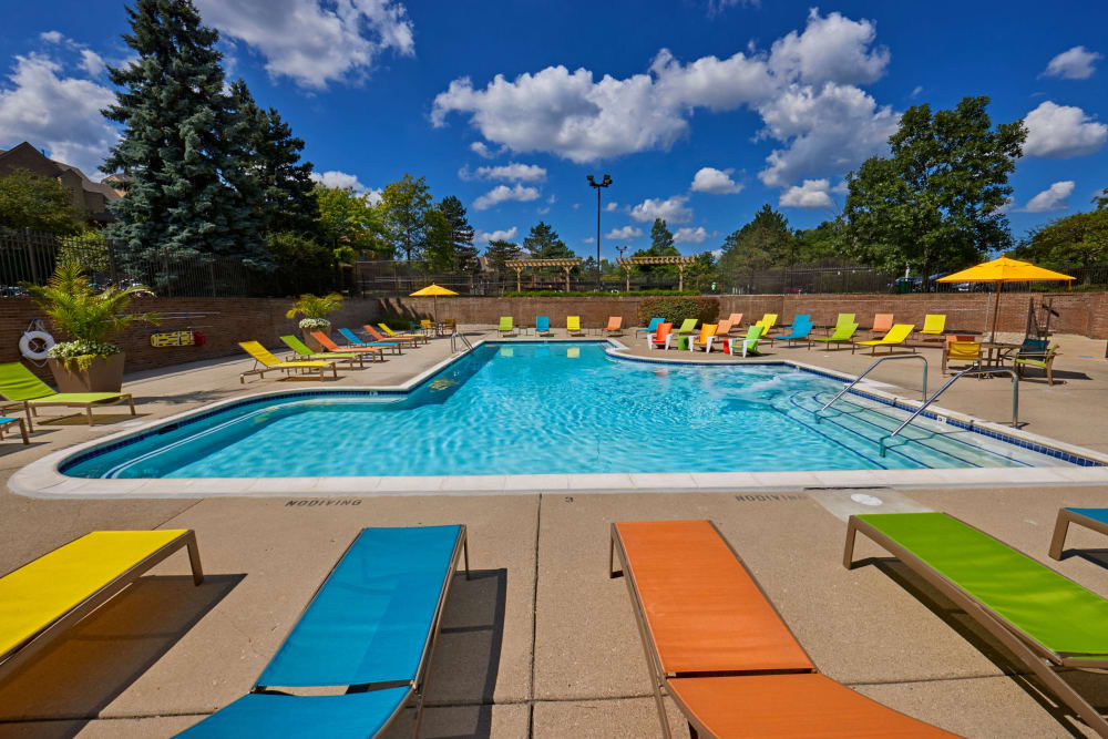 Colorful lounge chairs by the outdoor swimming pool at Saddle Creek Apartments in Novi, Michigan
