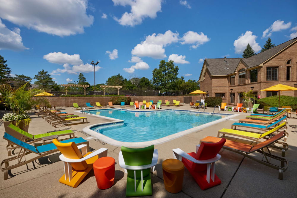 Swimming pool surrounded by lounge chairs on the expansive pool deck at Saddle Creek Apartments in Novi, Michigan