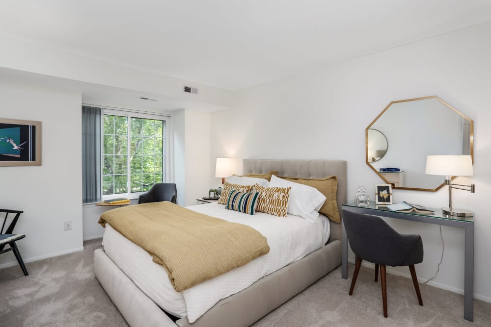 Model bedroom with a queen-size bed and desk at Saddle Creek Apartments in Novi, Michigan