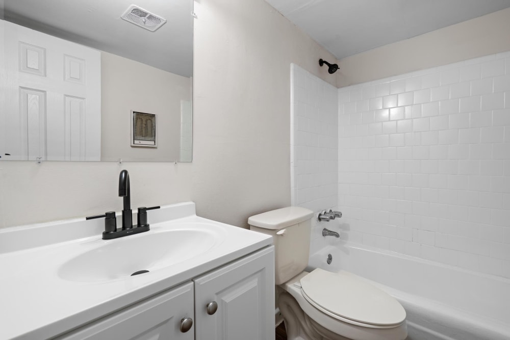 White cabinets and a full bathtub in an apartment bathroom at Cobbs Creek Apartment Homes in Decatur, Georgia
