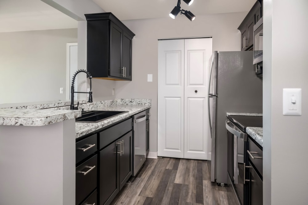 Kitchen with stainless steel appliances and dark wood cabinets at Waters Edge Apartments in Lansing, Michigan