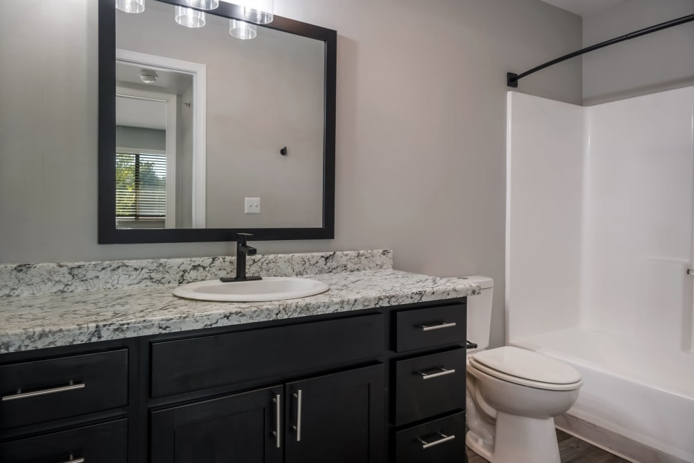 Bathroom with shower bathtub and large vanity mirror at Waters Edge Apartments in Lansing, Michigan
