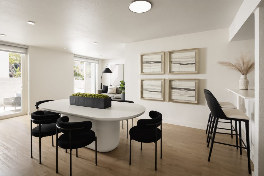A furnished dining room with table and chair along with artwork on the wall at Dolphin Marina Apartments in Marina Del Rey, California