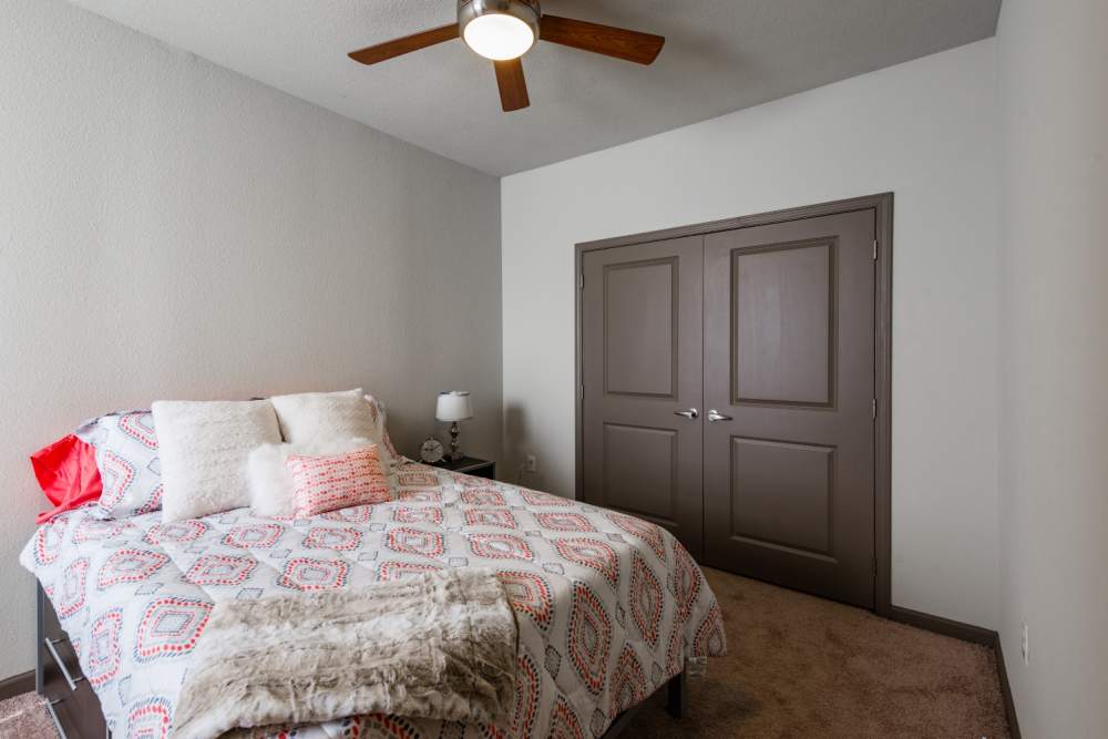 Carpeted bedroom with full size bed and ceiling fan at The Quarters at Stillwater in Stillwater, Oklahoma