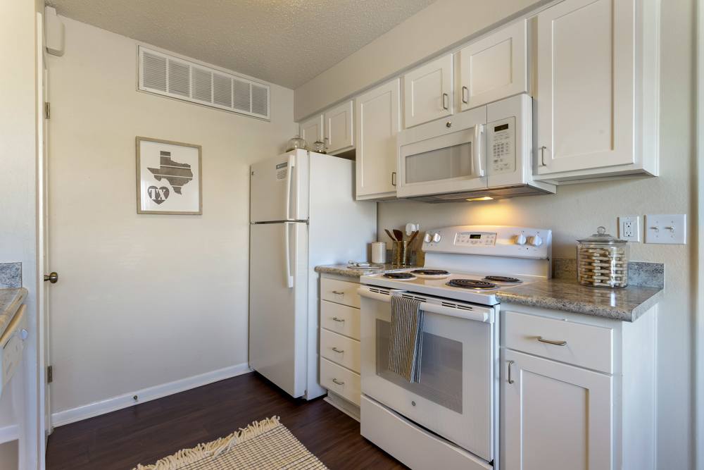 Full kitchen with white cabinets at The Landing at College Station in College Station, Texas