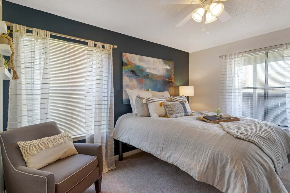 Large bedroom with accent chair and ceiling fan at The Landing at College Station in College Station, Texas