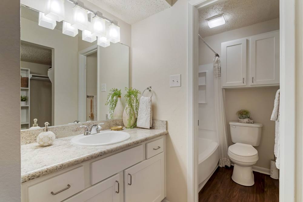 Apartment bathroom with large mirror at The Landing at College Station in College Station, Texas