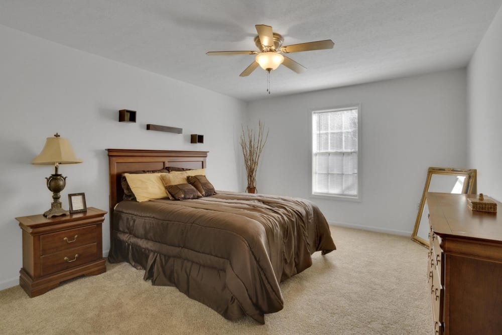 An apartment bedroom with a ceiling fan at The Pines at Peachtree in Columbus, Georgia