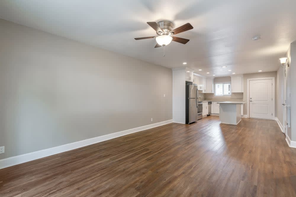 Apartment living area and kitchen with wood-style flooring and a ceiling fan at Pentagon Apartments in Fremont, California