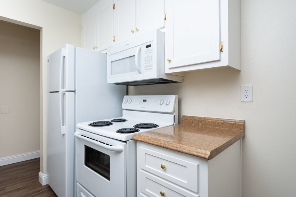 Kitchen with refrigerator, stove, and microwave at Bayfair Apartments in San Lorenzo, California