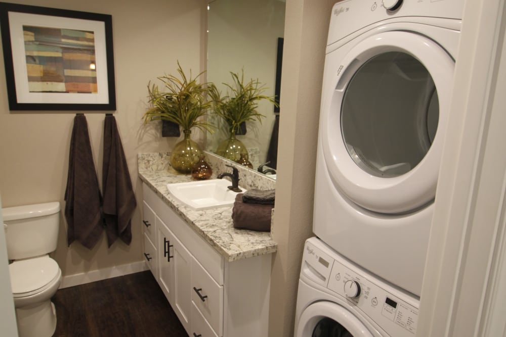Stacked washer and dryer next to the bathroom of a model home at Ramblewood Apartments in Fremont, California