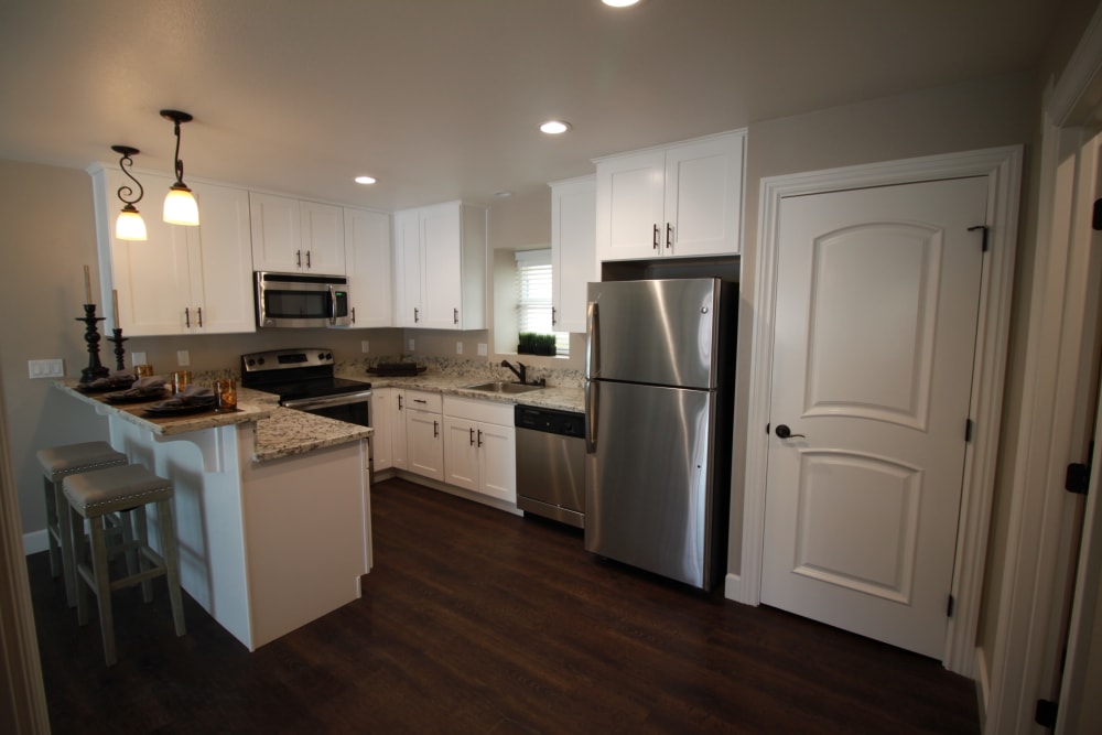 Fully equipped kitchen with white Shaker-style cabinets, stainless-steel appliances, and a breakfast bar at Ramblewood Apartments in Fremont, California